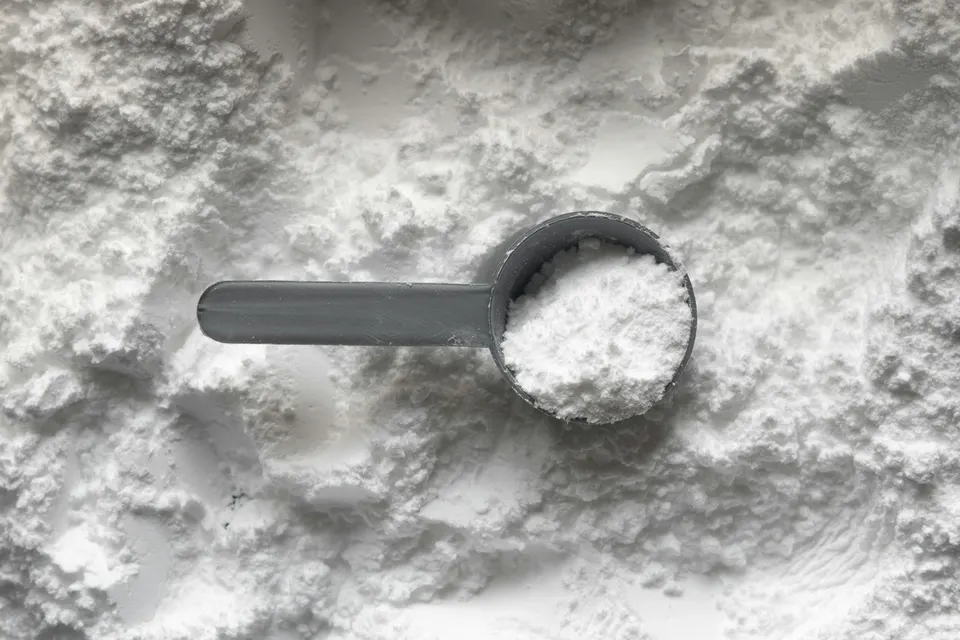Cacito de plástico gris lleno de polvo blanco sobre un montón de polvo